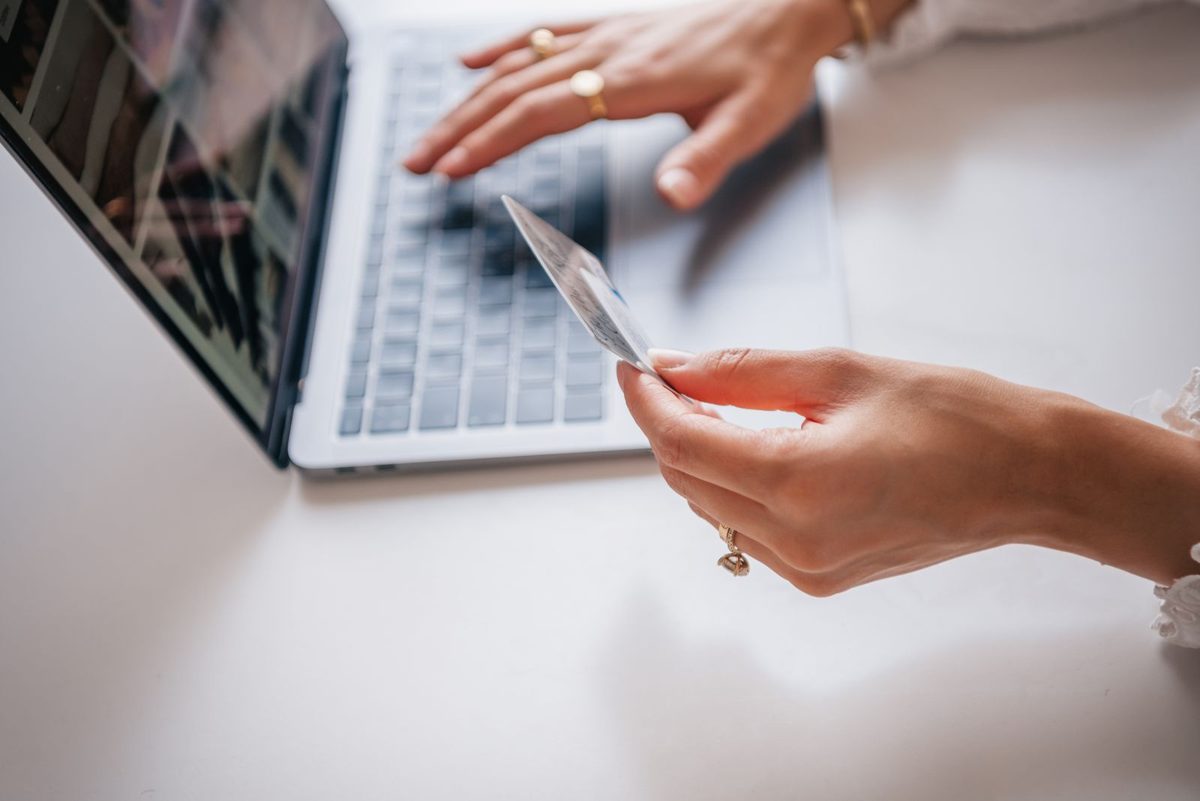 Someone holding a credit card while typing on a laptop, the kind of number not to share with ChatGPT